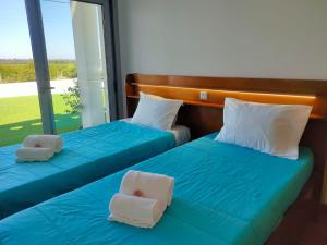 two beds in a room with blue sheets and white pillows at Moradia Faria in Fataca