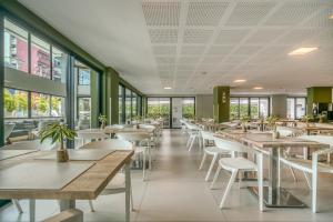 a restaurant with tables and chairs and windows at Porto Kaeté Hotel in Maceió