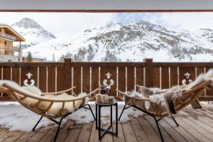a deck with two chairs and a table and snow covered mountains at Grand Pré in Val dʼIsère
