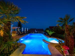 uma piscina à noite com palmeiras em Apartment Villa Andjelka-3 by Interhome em Trogir