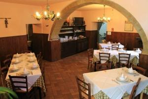 a restaurant with white tables and chairs and a kitchen at Guerrin Meschino in Montemonaco