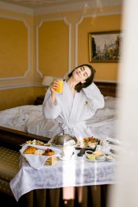 una donna seduta nel letto con un vassoio di cibo di Grand Hotel Emerald a San Pietroburgo