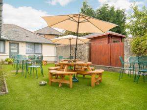 a picnic table with an umbrella on a lawn at Kirkstyle Hotel in Biggar