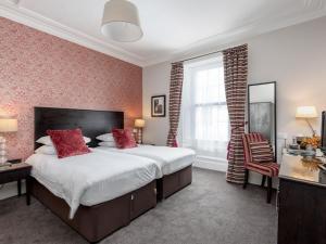a bedroom with a large bed with red pillows at Kirkstyle Hotel in Biggar