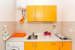Apartments Elelu في دوبروفنيك: مطبخ فيه دواليب صفراء ومغسلة