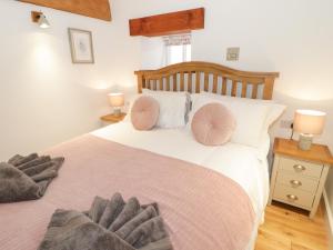 a bedroom with a bed with pink pillows on it at The Shippon in Llanrwst