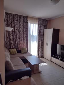Una sala de estar con un sofá y un televisor. en Messembria Resort, en Sunny Beach