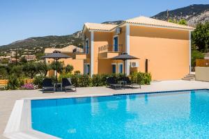 a villa with a swimming pool in front of a house at Afrato Village Sea View apartments in Trapezaki