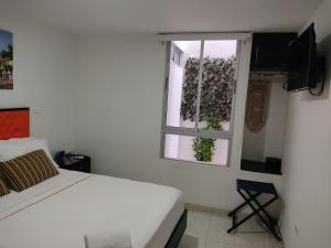 a white bedroom with a bed and a window at Escala Hotel in Valledupar