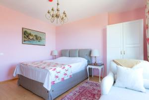 1 dormitorio con paredes rosas, 1 cama y lámpara de araña en Luxury 3-bedroom villa in Sozopolis with sea view en Sozopol