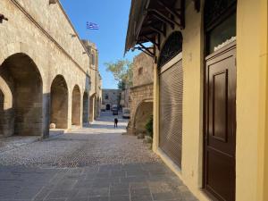 an alley with arches and a person walking down a street at Rhodes Old Town Harmony Suite in Rhodes Town