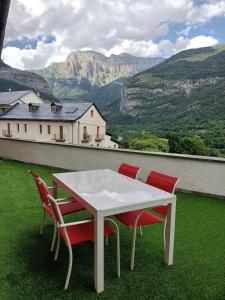 una mesa blanca y 4 sillas en un techo con montañas en El Mirador de Ordesa, en Torla