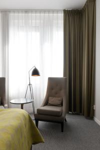 een slaapkamer met een bed, een stoel en een lamp bij Elite Hotel Ideon, Lund in Lund