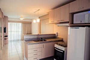 a kitchen with a sink and a white refrigerator at Beach Class Fortaleza by AM in Fortaleza