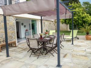 een tafel en stoelen onder een parasol op een patio bij Apartment Le Mas Line by Interhome in Le Brulat