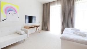 a white room with a bed and a couch and a tv at BASKE VILLA in Martinske Hole