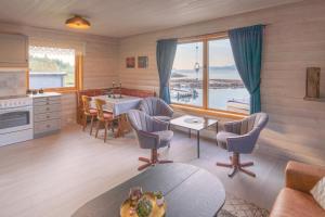 a living room with a kitchen and a table with chairs at Laukvik Senja in Botnhamn