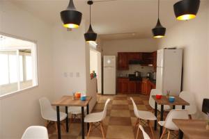 a kitchen and dining room with tables and white chairs at Real Ros Hostel in Rosario