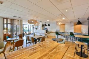 a restaurant with a large wooden table and chairs at Hôtel & Spa FACE À LA MER in Merville-Franceville-Plage