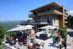 a building with tables and chairs and umbrellas at "La Cabane" de l'hôtel Le Tourisme in Zonza