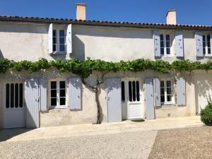 uma casa velha com portas brancas e hera em Maison de charme LA ROCHELLE ILE DE RE em Dompierre-sur-Mer