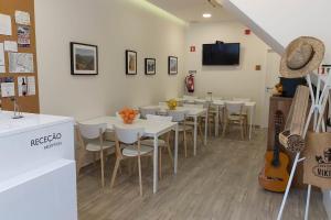 un restaurante con mesas y sillas blancas y TV en Hostel Douro Backpackers, en Pinhão
