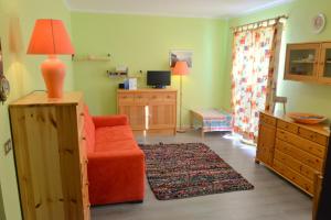a living room with an orange chair and a dresser at House La Motta by Holiday World in Borgata Sestriere