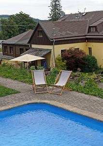 two chairs sitting next to a swimming pool at Penzion Jizera Malá Skála in Malá Skála