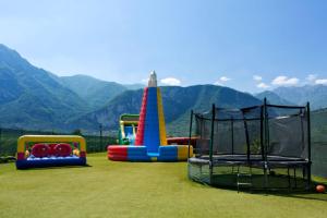 a group of playground equipment on a field with mountains in the background at Hotel Campagnola in Riva del Garda