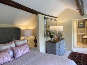 a bedroom with a bed and a dresser and a mirror at Vine Cottage in Chipping Campden
