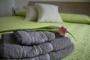 una pila de toallas con una flor encima de la cama en Home & Breakfast La Madonnina 013136-CNI-00001, en Lurago D'Erba 