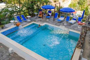 a swimming pool with chairs and umbrellas at Hotel Angelino in Ischia