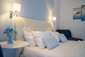 - un lit avec des oreillers blancs et une table avec un vase de fleurs dans l'établissement Sotto le Stelle ai Decumani, à Naples