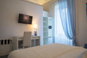 a bedroom with a bed and a desk and a television at Sotto le Stelle ai Decumani in Naples