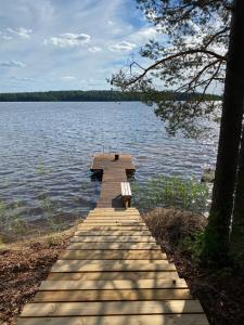 a wooden dock with a bench sitting on top of a lake at Lakeland Cabins fi in Huopanankoski