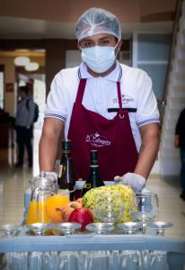 a man wearing a mask standing in front of a table of food at HOTEL AVENIDA in Tacna