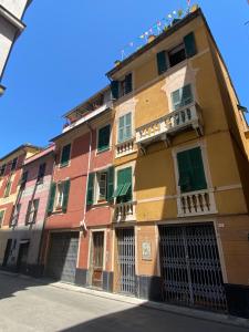 a colorful building with green shutters on a street at COME a CASA TUA - LAVAGNA in Lavagna