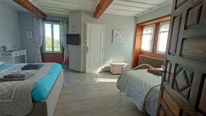 a bedroom with two beds and a tv and windows at LA DAME FINES in Puybegon