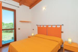 una camera con letto arancione e finestra di Villa Circe a Santa Teresa di Gallura