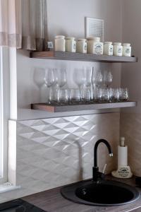 a kitchen counter with a sink and glasses on shelves at Be my apartman in Odorheiu Secuiesc