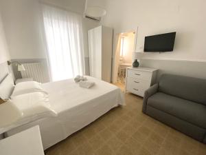 een slaapkamer met een bed, een stoel en een televisie bij Domina Living Apartments - Presepe in Bisceglie