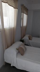 a bedroom with two beds with white sheets and curtains at El Pez Naranja in Zahara de los Atunes