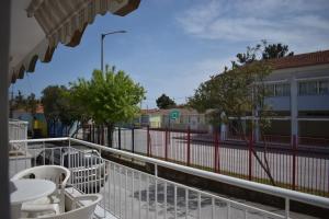 a balcony with white chairs and a fence and a street at Nearby the sea in Asprovalta