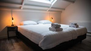a bedroom with a large white bed with towels on it at Welcome in - Oranjezon - Vakantiehuis 6 personen in Vrouwenpolder +25 photos