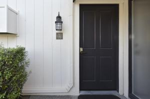 eine schwarze Tür an einem weißen Haus mit einer Lampe in der Unterkunft 657 Cottages at Silverado residence in Napa