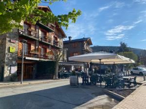 un patio avec des tables et des parasols en face d'un bâtiment dans l'établissement Hotel Esquirol, à Llívia