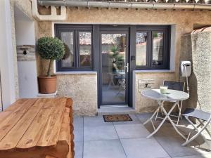 een patio met een houten tafel en een witte tafel bij Studio tout confort, terrasse, calme Moustiers #7 in Moustiers-Sainte-Marie