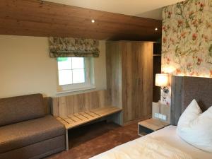 a bedroom with a bed and a bench and a window at Gasthof Wiesenhof in Strobl