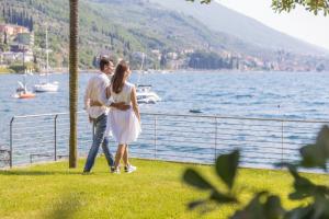 un homme et une femme debout à côté d'une masse d'eau dans l'établissement Hotel Val Di Sogno - Adults Only, à Malcesine