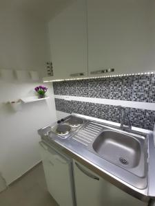 - une cuisine avec un évier et un mur en carrelage dans l'établissement Apartman Danilo, à Ulcinj